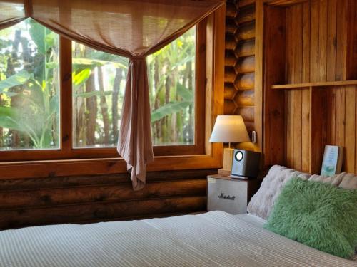 a bedroom with a bed with a window and a lamp at Mộc An Nhiên Farmstay in Pleiku