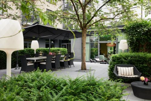 a patio with a table and chairs and an umbrella at The George Hamburg in Hamburg
