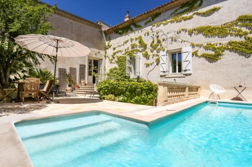 - une piscine avec un parasol en face d'une maison dans l'établissement Villa La Fontaine by Villa Plus, à Capestang