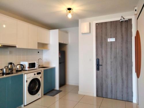 a kitchen with a washing machine and a door at Continew Residence by HomeBrickz in Kuala Lumpur