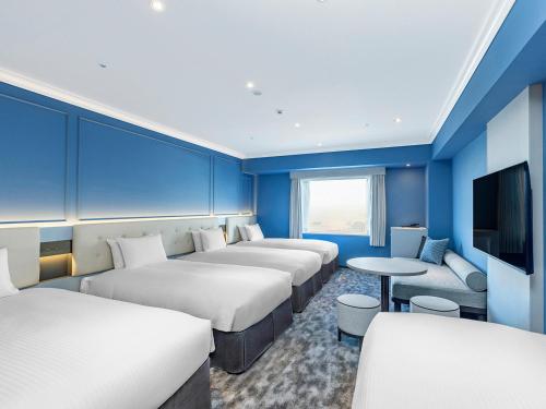 a hotel room with four beds and a flat screen tv at Oriental Hotel Tokyo Bay in Urayasu