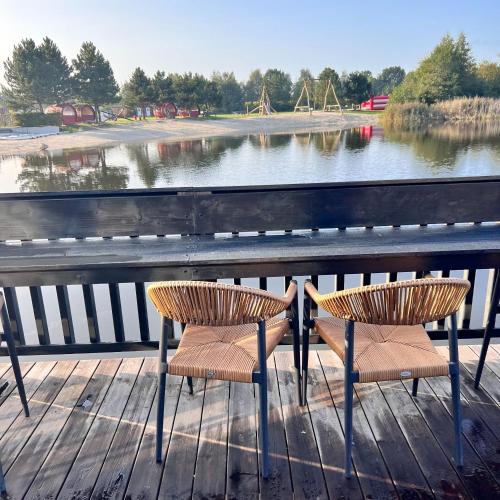 two chairs sitting on a wooden deck next to a lake at EMSLAND-CAMP in Haar