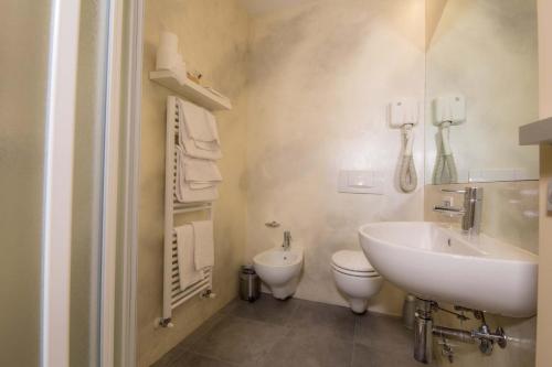a white bathroom with a sink and a toilet at Albergo Silvio in Bellagio