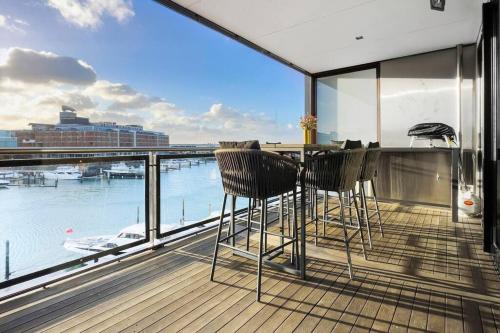 a balcony with two chairs and a bar with a view of the water at Pacific Residence in Auckland