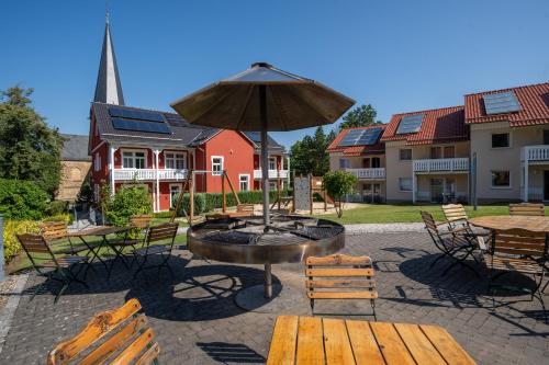 a patio with a fountain with benches and an umbrella at Hotelpark Bodetal mit Ferienwohnungen in Thale