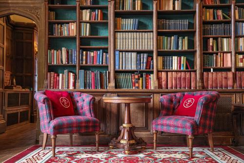 two chairs and a table in a library with books at Thornbury Castle - A Relais & Chateaux Hotel in Thornbury