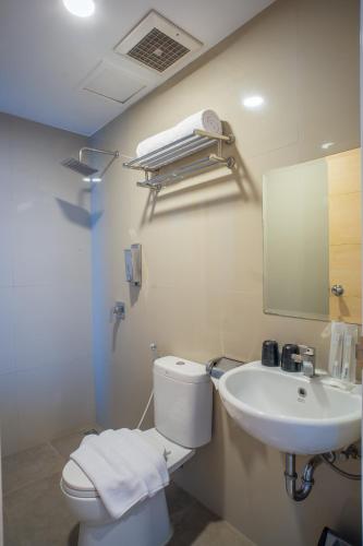 a bathroom with a white toilet and a sink at Triizz Hotel Semarang in Semarang