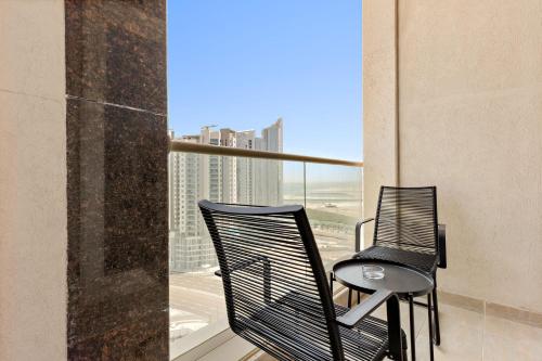 two chairs on a balcony with a view of the city at Silkhaus Vacation Homes Chic 1BDR near Canal at Al Reem Island in Abu Dhabi