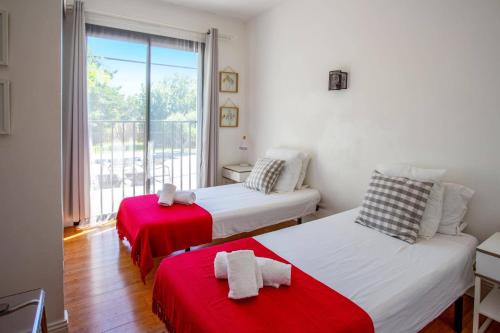 a bedroom with two beds with red sheets and a window at Villa Pezenas by Villa Plus in Pézenas