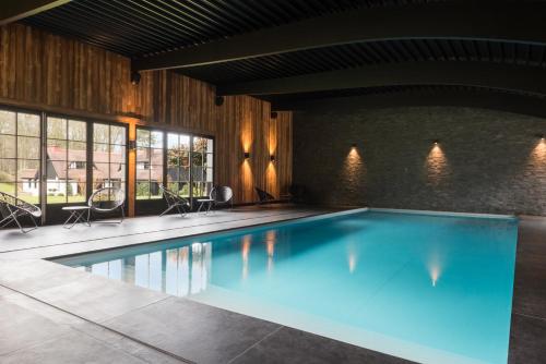 a large swimming pool with blue water in a building at Les Pins de César - La campagne d'Etretat in Saint-Jouin-Bruneval