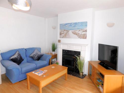 a living room with a blue couch and a fireplace at Philips Cottage in Sheringham