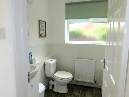 a bathroom with a toilet and a sink and a window at Philips Cottage in Sheringham