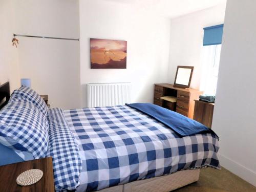 a bedroom with a blue and white checkered bed at Philips Cottage in Sheringham