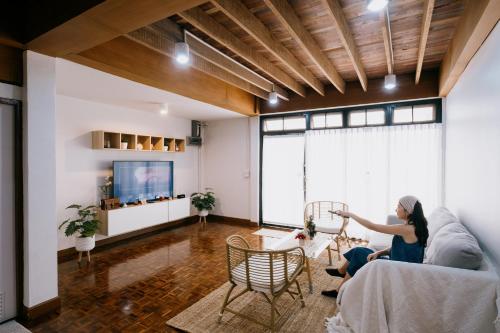 a woman sitting on a couch in a living room at Home Story Hostel Chiang Mai in Chiang Mai