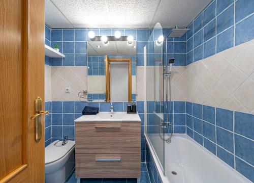 een blauw betegelde badkamer met een bad en een wastafel bij Apartamento Las Joyas in Estepona