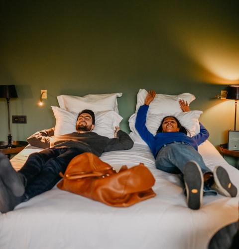 two people laying on top of a bed at Les Pins de César - La campagne d'Etretat in Saint-Jouin-Bruneval