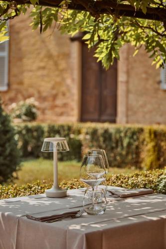 a table with wine glasses and a lamp on it at Relais Castello di Razzano in Alfiano Natta