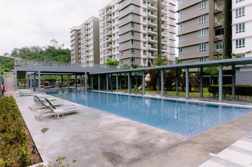 a large swimming pool with lounge chairs in front of a building at Trival Misty Cottage Homestay Sri Indah Sandakan in Sandakan