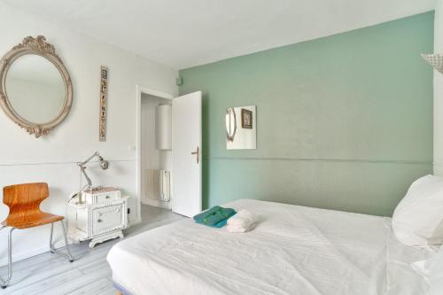 une chambre avec un lit blanc et un miroir dans l'établissement Charmant appartement proche du Canal de L'Ourcq, à Pantin
