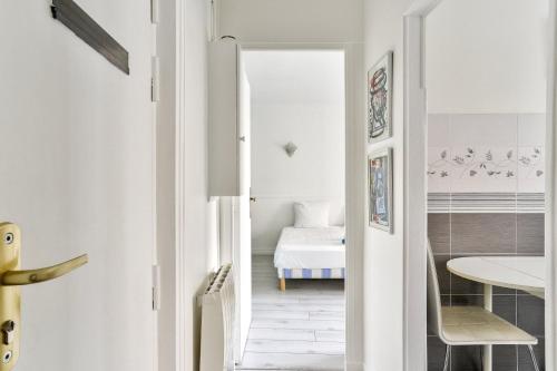 - un couloir blanc avec une chambre dotée d'un lit dans l'établissement Charmant appartement proche du Canal de L'Ourcq, à Pantin