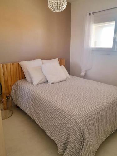 une chambre avec un lit avec des oreillers blancs et une fenêtre dans l'établissement La PLage, à Port-la-Nouvelle