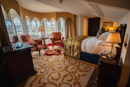 a hotel room with a bed and chairs and windows at Thornbury Castle - A Relais & Chateaux Hotel in Thornbury