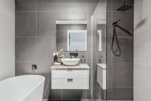 a bathroom with a white sink and a shower at Luxurious Hobart Holiday Home with Stunning Bay Views - Affordable, Family-Friendly, and Stylish in Sorell