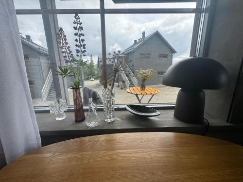 a table with a lamp and vases on a window at Funäsdalshöjden Funäsdalen in Funäsdalen
