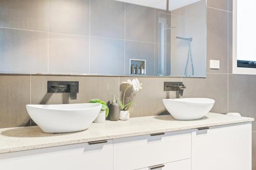 two white bowls on a counter in a bathroom at Luxurious Hobart Holiday Home with Stunning Bay Views - Affordable, Family-Friendly, and Stylish in Sorell