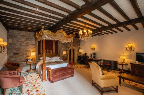 a bedroom with a bed and a couch and chairs at Thornbury Castle - A Relais & Chateaux Hotel in Thornbury