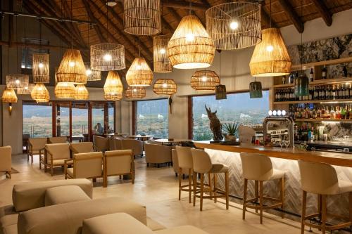 a restaurant with a bar with chairs and lights at Aquila Private Game Reserve & Spa in Touwsrivier