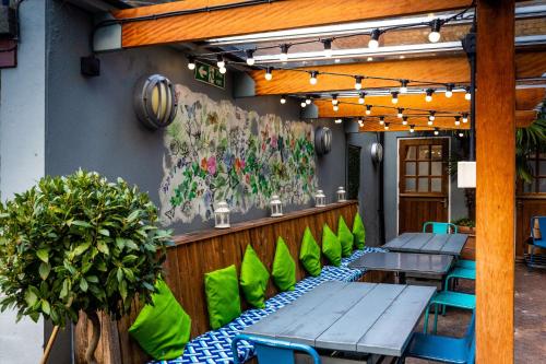 a patio with tables and green chairs on a building at The Brook Green Hotel in London