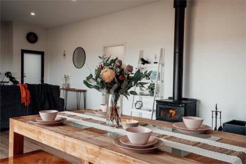 a living room with a wooden table with a vase of flowers at Luxurious Hobart Holiday Home with Stunning Bay Views - Affordable, Family-Friendly, and Stylish in Sorell
