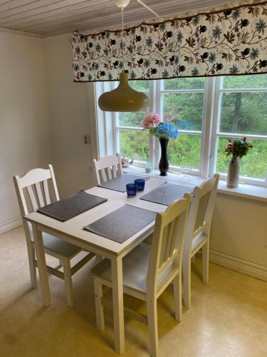 a dining room table with white chairs and a window at Bäckefors vandrarhem in Bäckefors