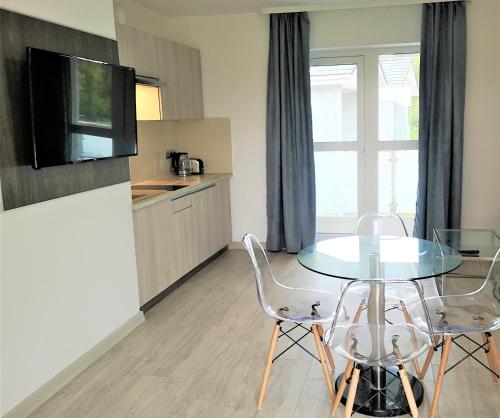 a kitchen with a glass table and two chairs at Srebrna Wydma Resort in Dąbki