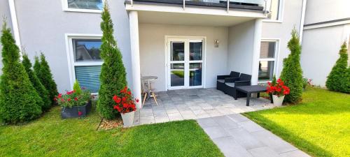 a white house with a patio with red flowers at Srebrna Wydma Resort in Dąbki