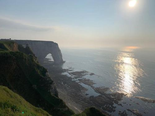 - une vue sur l'océan et le coucher de soleil sur une falaise dans l'établissement Charmante maisonnette à 2 pas de la mer !, à Étretat