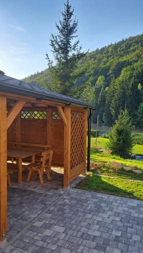 a wooden pavilion with a picnic table in a field at Willa Sowia nowe apartamenty nad górskim potokiem zachwycający widok na góry in Stronie Śląskie