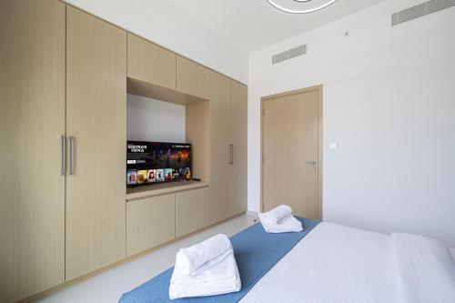 a bedroom with a bed with a tv and cabinets at 5 Minute Walk to The Fountains! Full Burj Khalifa View! 5-star Pool & Gym! in Dubai