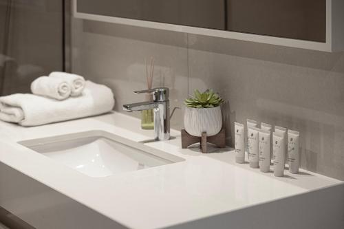 a white bathroom sink with a faucet and towels at 5 Minute Walk to The Fountains! Full Burj Khalifa View! 5-star Pool & Gym! in Dubai