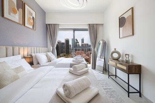 a white bedroom with a large bed and a window at 5 Minute Walk to The Fountains! Full Burj Khalifa View! 5-star Pool & Gym! in Dubai