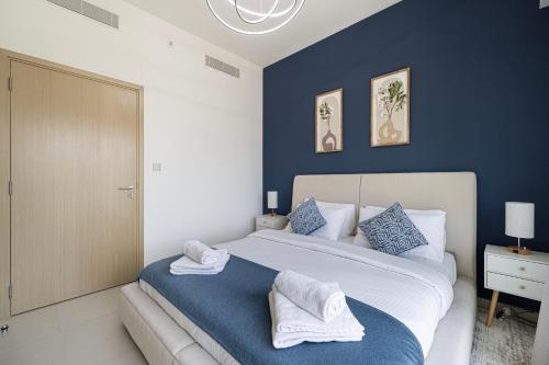 a bedroom with a large white bed with blue walls at 5 Minute Walk to The Fountains! Full Burj Khalifa View! 5-star Pool & Gym! in Dubai