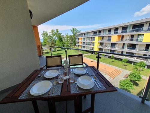 a table with plates and glasses on a balcony at Casa Romana Aqua Apartman in Siófok