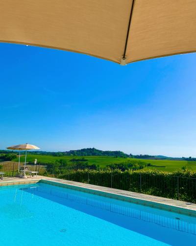 a swimming pool with an umbrella and a view at Relais Castello di Razzano in Alfiano Natta