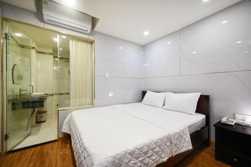 a bedroom with a white bed and a shower at Gia Hoa Airport Hotel in Ho Chi Minh City