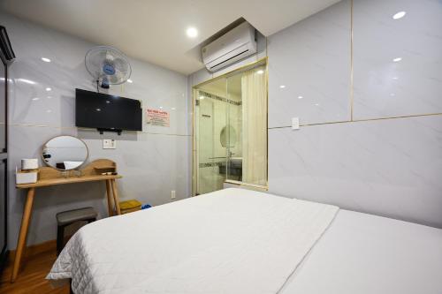 a bedroom with a white bed and a tv at Gia Hoa Airport Hotel in Ho Chi Minh City