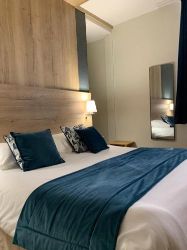a bedroom with a large bed with blue pillows at Ambassadeur Hotel - Cherbourg Port de Plaisance in Cherbourg en Cotentin