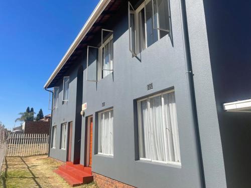 a gray house with white windows and a red door at Palmar Hotel in Johannesburg