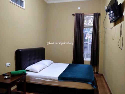 パレンバンにあるRian Kost - Hotel Penginapan Murah Pusat Kota Palembangのベッドルーム(ベッド1台、テレビ、窓付)