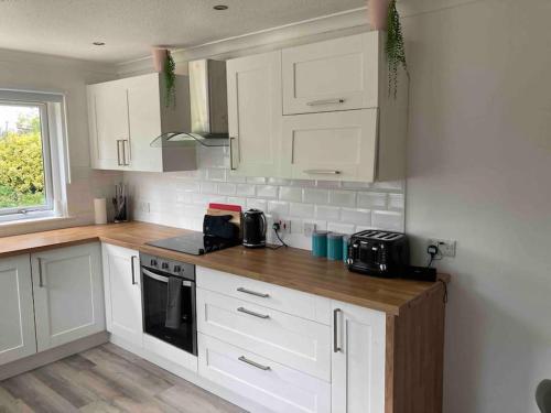 eine Küche mit weißen Schränken und einer Arbeitsplatte in der Unterkunft Cottage in heart of Perthshire in New Scone